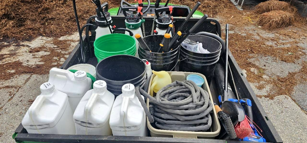 Bed of The Garden Sage field rig organized with buckets, jugs, hoses, watering cans, hand tools, and cleanup gear