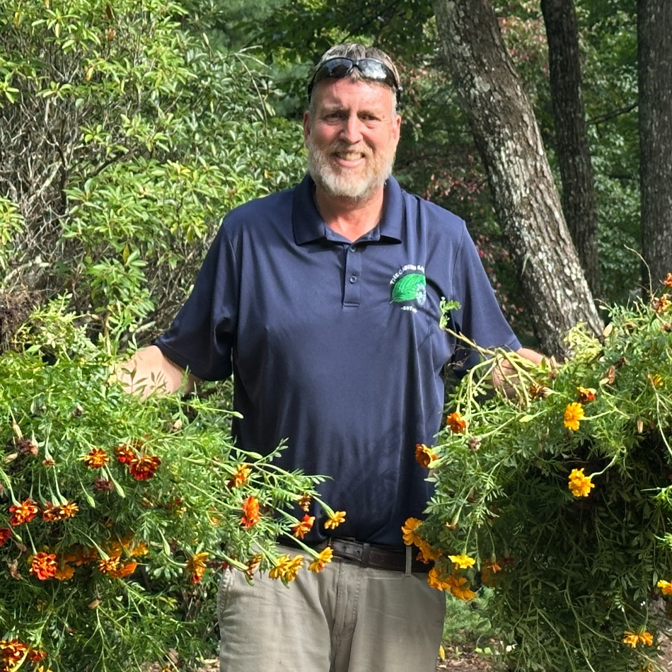 Josh among flowering garden plants, wearing his Garden Sage shirt